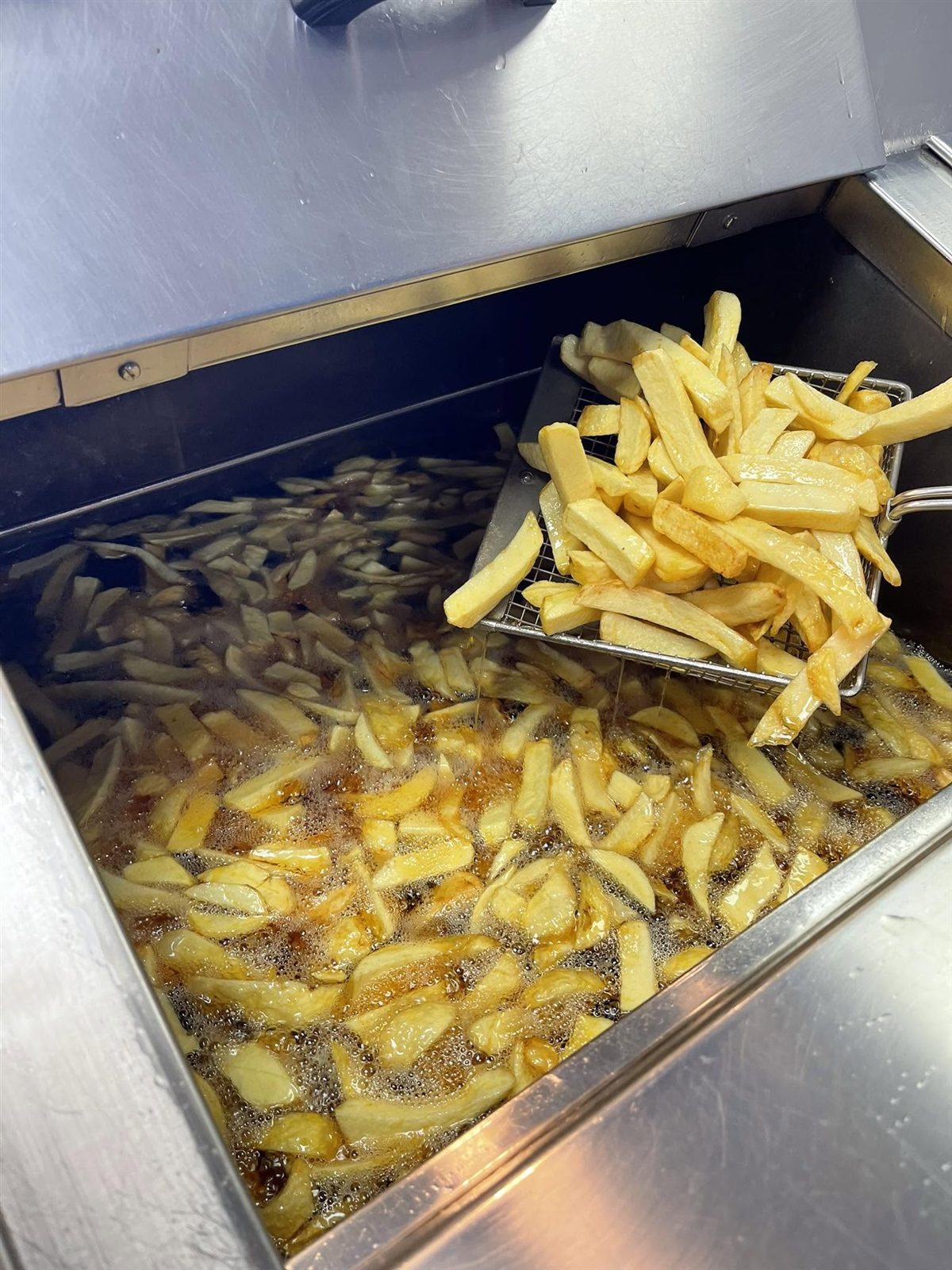 Golden chips being lifted fresh from the fryer