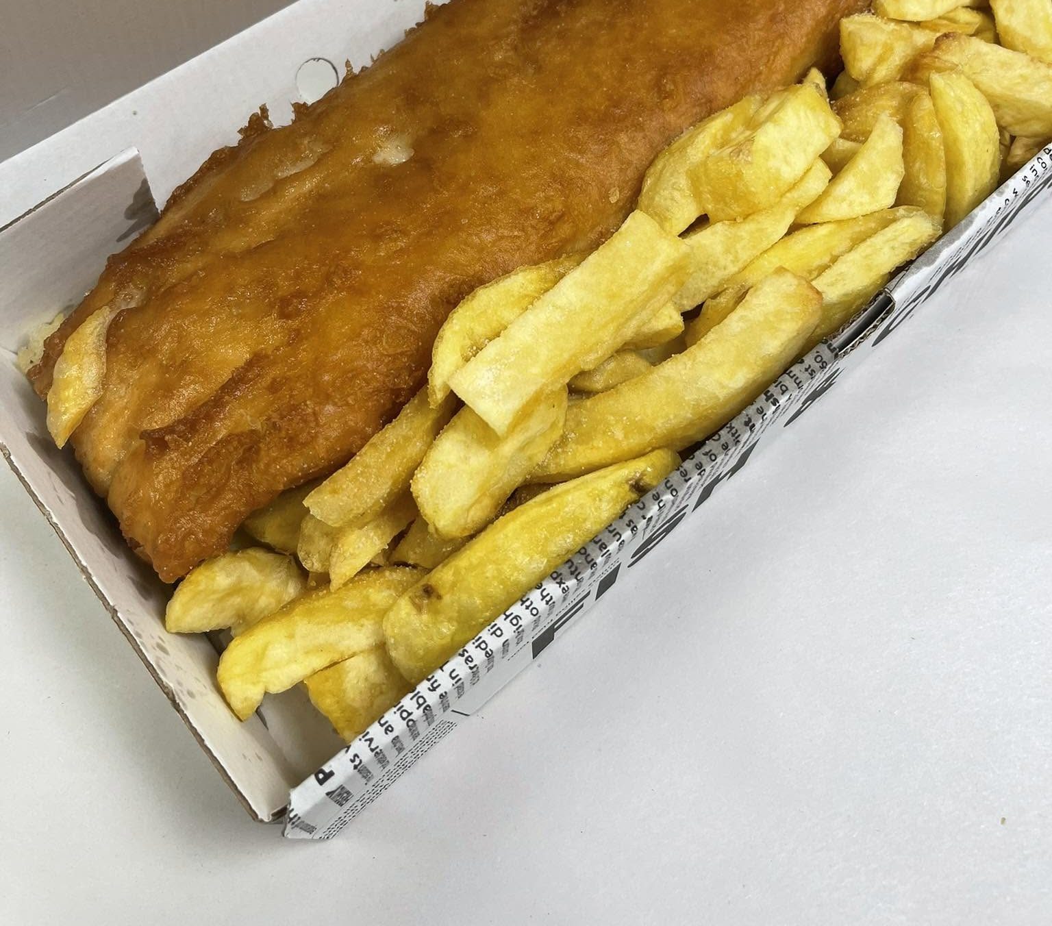 Freshly fried fish and chips in a St James Fish Bar takeaway box